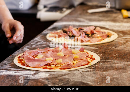 Cook toppings setzen auf zwei Pizzas. Stockfoto