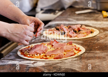 Cook toppings setzen auf zwei Pizzas. Stockfoto