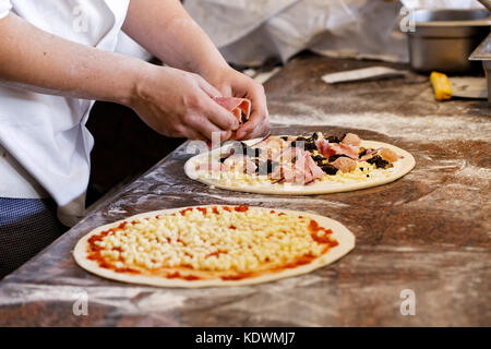 Cook toppings setzen auf zwei Pizzas. Stockfoto