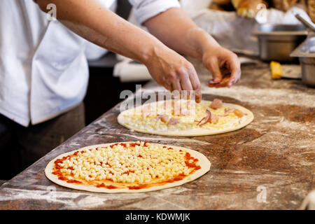 Cook toppings setzen auf zwei Pizzas. Stockfoto