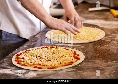 Cook toppings setzen auf zwei Pizzas. Stockfoto