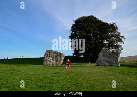 Frau zu Fuß durch standig mit Steinen Henge Steinkreis von Avebury, Wiltshire, Großbritannien Stockfoto