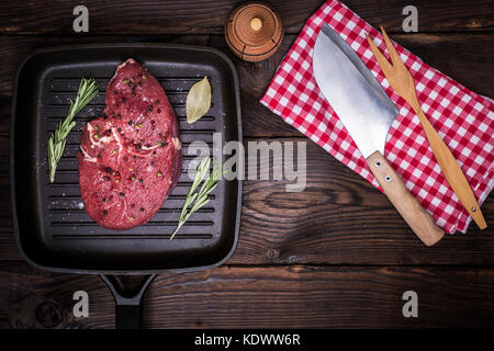 Rohes Rindfleisch Steak mit Gewürzen auf eine Schwarze Pfanne, nächste Messer, Ansicht von oben, leeren Raum in der Mitte Stockfoto