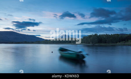 Breaking Dawn über ein Boot vertäut am Loch Maree, mit Slioch jenseits, Wester Ross, Schottland Stockfoto