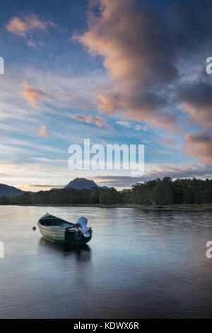 Breaking Dawn über ein Boot vertäut am Loch Maree, mit Slioch jenseits, Wester Ross, Schottland Stockfoto