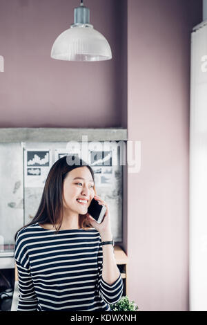 Asien Geschäftsfrau Eigentümer tragen casual Tuch Gespräch am Handy im Home Office Arbeitsplatz für Kunden kontaktieren, Office Lifestyle mit Technologie Stockfoto