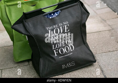 George Bernard Shaw zitiert „There is no love sincerer than the Love of Food“ in M&S, Marks and Spencer, Marks & Spencer's Store, zwei wiederverwendbare, grüne und schwarze Plastiktaschen aus 100 % recyceltem Kunststoff für Life on the Pavement, Preston, Großbritannien Stockfoto