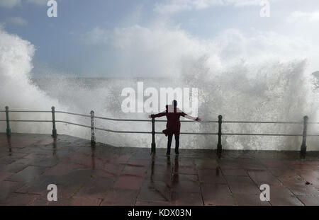 Eine Frau sprankt, als Wellen an der Meereswand in Penzanze, Cornwall, aufprallen, als Hurrikan Ophelia Großbritannien und Irland mit Böen von bis zu 80 mph trifft. Stockfoto