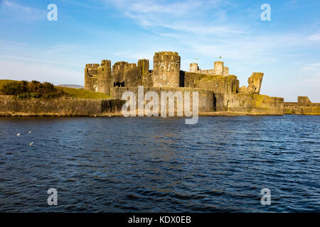 Wassergraben, der Wände und der schiefe Turm von Caerphilly Castle im niedrigen Abendlicht, Caerphilly, Wales, UK Stockfoto