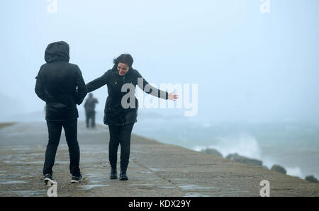 Menschen an der Pier-Wand während des Sturms Ophelia am East Pier in Howth, Dublin, Irland, als Hurkan Ophelia Großbritannien und Irland mit Böen von bis zu 80 km/h bekämpft. Stockfoto