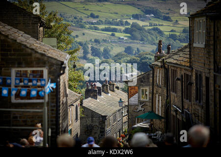 Pennines Dorf, Haworth in West Yorkshire, England. terrassierten Häuser und Geschäfte auf der steilen Straße Stockfoto