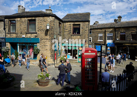 Pennines Dorf, Haworth in West Yorkshire, England. terrassierten Häuser und Geschäfte auf der steilen Straße Stockfoto