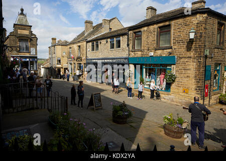 Pennines Dorf, Haworth in West Yorkshire, England. terrassierten Häuser und Geschäfte auf der steilen Straße Stockfoto