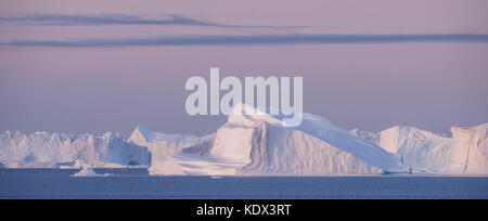 Grönland, Scoresbysund alias Scoresby Sund, Nordvestfjord. Panoramablick auf den Sonnenaufgang über riesige Eisberge. Stockfoto