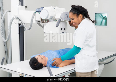 Junge weibliche Radiologen unter x-ray von erwachsenen Patienten, der auf einer Trage im Untersuchungsraum Stockfoto