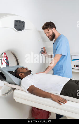 Junge männliche Professional zu starten CT auf Patienten im Untersuchungsraum Scan Stockfoto