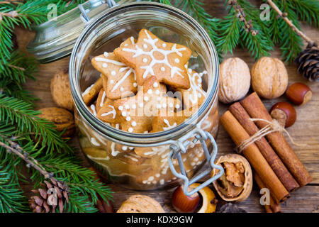 Lebkuchen weihnachtsplätzchen Sterne im Glas Glas mit Tannenzweigen, weihnachtliche Gewürze und Dekor Nahaufnahme Stockfoto