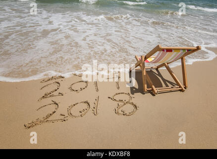 Liege mit 2018 und Inschrift 2017 in Sand geschrieben schreibt am tropischen Strand. Stockfoto