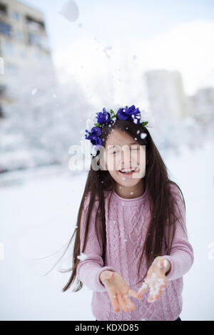 Kleines Mädchen Schnee bis in die Luft zu werfen, die Spaß haben. winter Szene Stockfoto