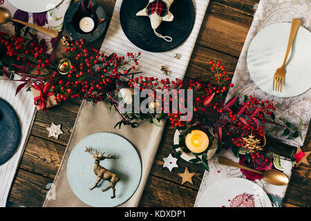 Urlaub Gold Gedeck, lustige Weihnachten Tabelle mit Ornamenten und natürlichen Beeren, auf Holztisch, Overhead schießen Stockfoto