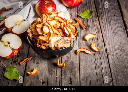 Hausgemachte sonnengetrockneten Bio Apfelscheiben, Crispy apple Chips, auf einer alten rustikalen Holztisch mit frischen Apfel und Zimt. Kopieren Sie Platz Stockfoto