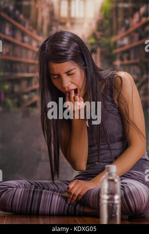 Schöne und einsame Mädchen leiden der appetitanregend, seine Finger in den Mund zu bewegen, mit einer Flasche Wasser vor in einem verschwommenen Hintergrund Erbrechen Stockfoto