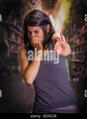 Schöne und einsame Mädchen leiden unter appetitanregend, halten sie in ihrer Hand ein Stück Schokolade und ihre Nase nicht die Schokolade riechen, in einem Hintergrund verschwommen zu tun Stockfoto