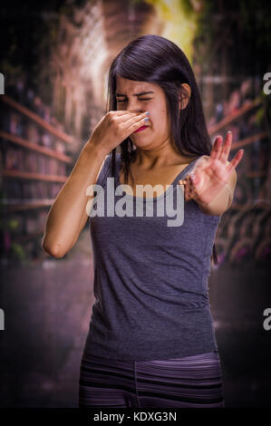 Schöne und einsame Mädchen leiden unter appetitanregend, halten sie in ihrer Hand ein Stück Schokolade und ihre Nase nicht die Schokolade riechen, in einem Hintergrund verschwommen zu tun Stockfoto