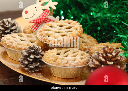 Weihnachten Mince Pies auf einen goldenen Schild mit weißem Rentier auf ein Holz Hintergrund Stockfoto