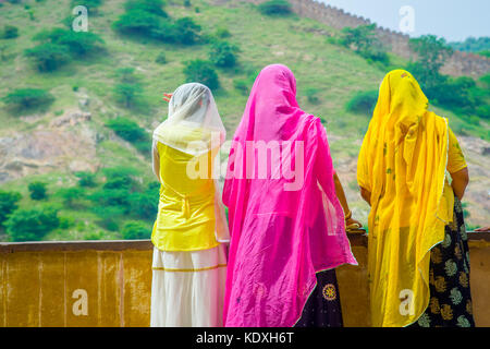 Amer, Indien - 19. September 2017: unbekannter Frauen in einer steinigen Wand posieren und trug eine gelbe und rosa Kleidung, und genießen den Blick auf den See maota in Fort Amber in Jaipur, Rajasthan, Indien Stockfoto