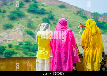 Amer, Indien - 19. September 2017: unbekannter Frauen in einer steinigen Wand posieren und trug eine gelbe und rosa Kleidung, und genießen den Blick auf den See maota in Fort Amber in Jaipur, Rajasthan, Indien Stockfoto