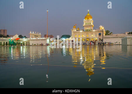 Delhi, Indien - 19. September 2017: unbekannte Menschen zu Fuß vor dem Hauptgebäude des Sikh Schreine von Delhi - Gurudwara Bangla Sahib. Das Hauptgebäude des Tempels beleuchtet ist und in sarowar Teich Wasser in Indien wider. Stockfoto