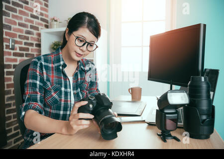 Erfolgreiche Ernst weibliche business Foto, die Frau mit der Kamera überprüfen Sie die Bild- und Sitzen am Schreibtisch bereit für Bodenfunktionen zu transportieren Stockfoto