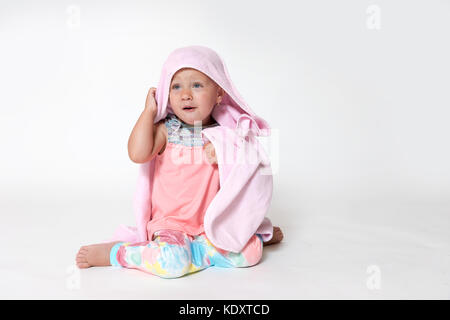 Studio geschossen von Smilling kleinkind Mädchen sitzt und in rosa Schlafanzug abgedeckt Stockfoto