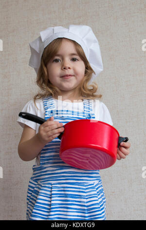 Portrait adorable kleine Mädchen in Chef hat Kochen. Mädchen hält ein pan Stockfoto