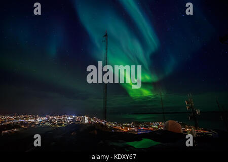 Grüne Wellen von Aurora Borealis mit leuchtenden Sterne über den Fjord und markierten Stadt, Nuuk, Grönland Stockfoto