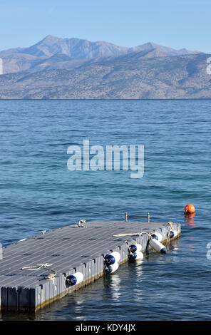 Ein schwimmender Ponton oder Anlegestelle an der Küste bei Kassiopi, Korfu, Griechenland am Meer auf die Berge von Albanien im Hintergrund. Stockfoto