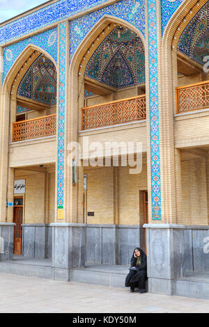 Provinz Fars, Shiraz, Iran - 19. April 2017: Shah Cheragh Moschee, eine unbekannte muslimische Frau in einem islamischen Schleier, Telefonieren, sitzen auf der s Stockfoto