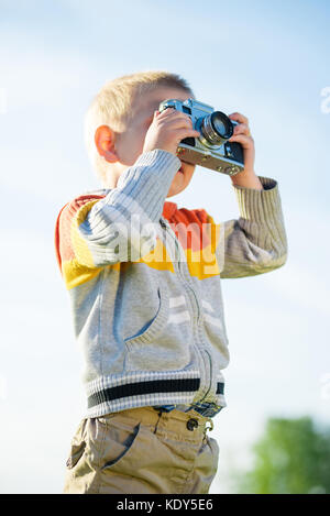 Kleiner Junge mit einer alten Kamera schießen im Freien. Stockfoto