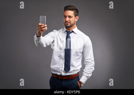 Ein hübscher junger Mann, wobei ein Selbstporträt mit seinem Handy Stockfoto