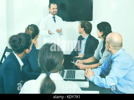 Positive effiziente Wissenschaftler präsentieren Bericht während der Sitzung im Büro Stockfoto