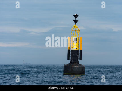 Der Rinne Stein Süden Kardinal marker Boje mit longships Leuchtturm im Hintergrund auf ein ruhiger Tag Stockfoto