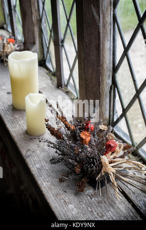 Die herbstlichen Erntedankfest getrocknete Blumen und Kerzen auf dem Fensterbrett an Weald und Downland Open Air Museum, Herbst, Singleton, Sussex, England Stockfoto