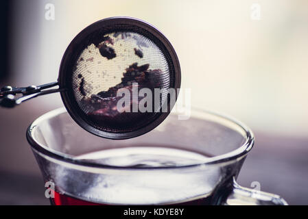 Glas schwarz oder rot Tee oder Kräuter Tee stainer auf hölzernen Tisch Stockfoto