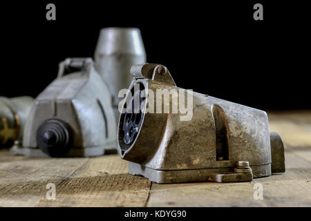 Alte Stecker und Buchse Hochspannung. Alte elektrische Zubehör. Holztisch, schwarzer Hintergrund Stockfoto