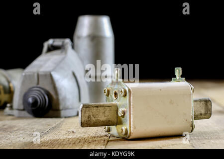 Alte Stecker und Buchse Hochspannung. Alte elektrische Zubehör. Holztisch, schwarzer Hintergrund Stockfoto