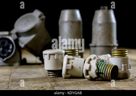 Alte Stecker und Buchse Hochspannung. Alte elektrische Zubehör. Holztisch, schwarzer Hintergrund Stockfoto