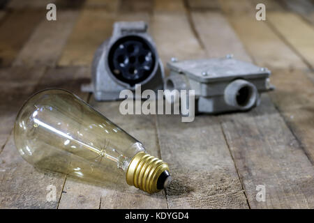 Alte Stecker und Buchse Hochspannung. Alte elektrische Zubehör. Holztisch, schwarzer Hintergrund Stockfoto