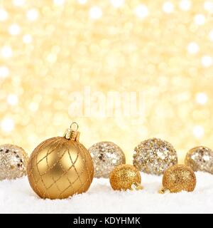 Golden Christmas Ornaments im Schnee mit glitzernden Gold Hintergrund Stockfoto