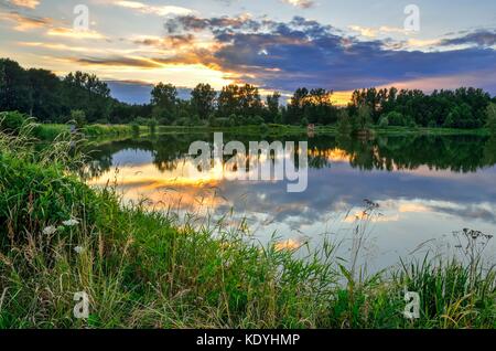Schönen Sommer Landschaft. Teich in der Landschaft in der fabelhaften Abend Farben. Stockfoto